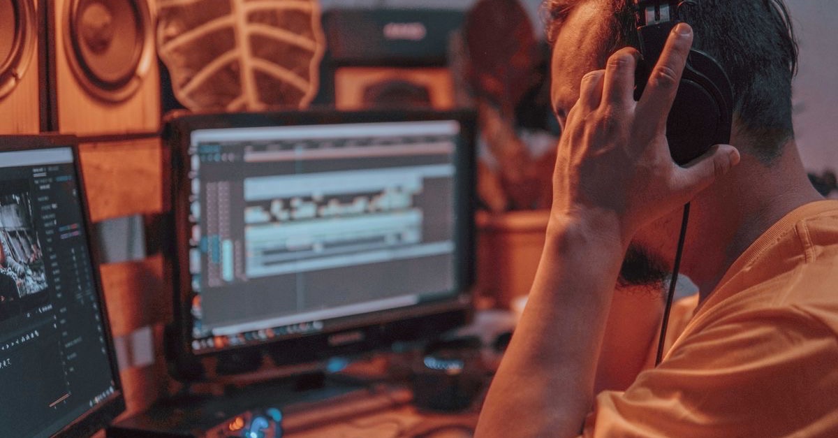 Audio engineer editing a podcast episode on a studio workstation while monitoring on headphones
