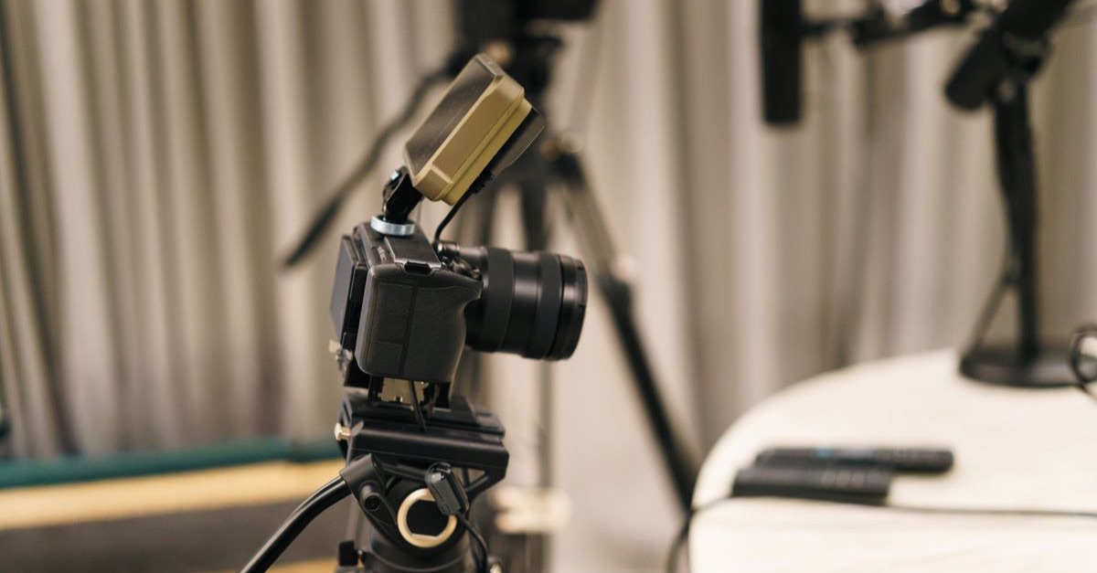 Camera on a tripod facing a microphone in a multi-camera video podcast studio