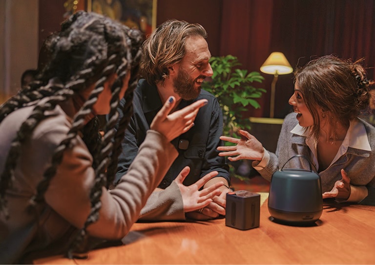 Three people talking around a table with the Nomono Sound Capsule recording between them