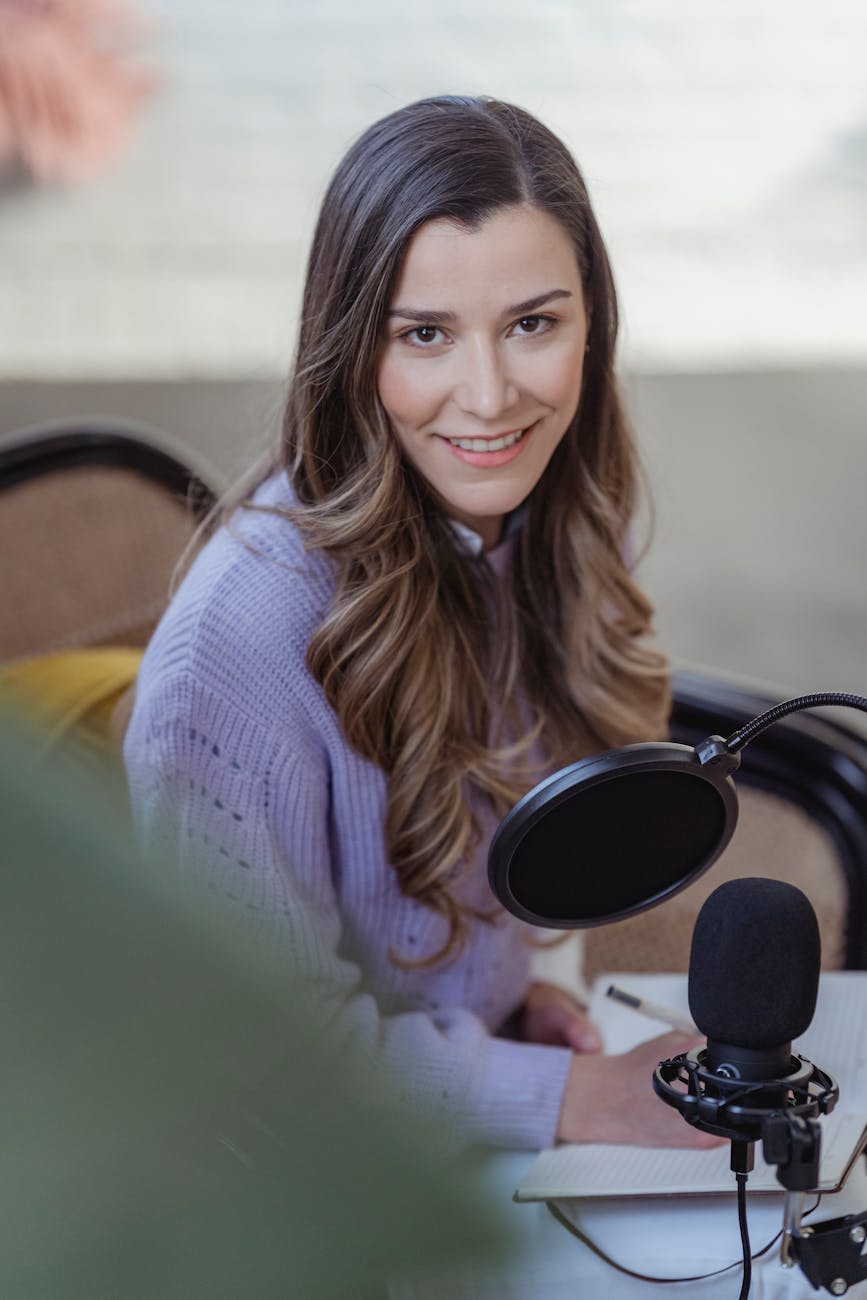 female near microphone writing notes in notepad in room